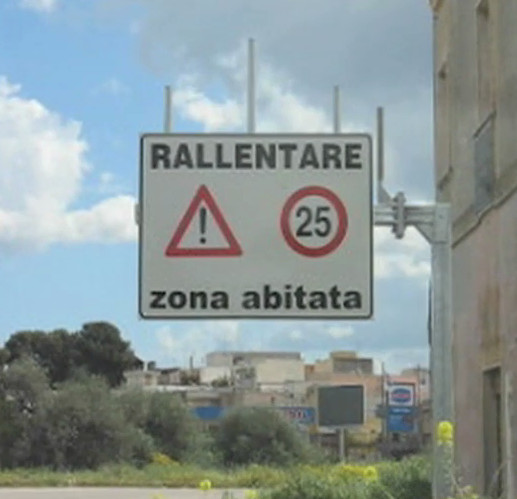 Cartello stradale "Rallentare zona abitata" e San Ferdinando di Puglia.