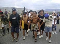 Un gruppo di indigeni trasporta un ferito, dopo gli scontri con la polizia.