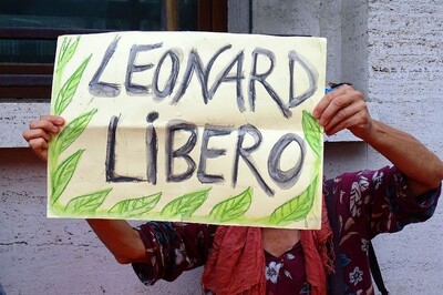 Attivista espone cartello chiedendo libertà per Leonard Peltier. 