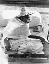 Foto che ritrae Gandhi intento a filare