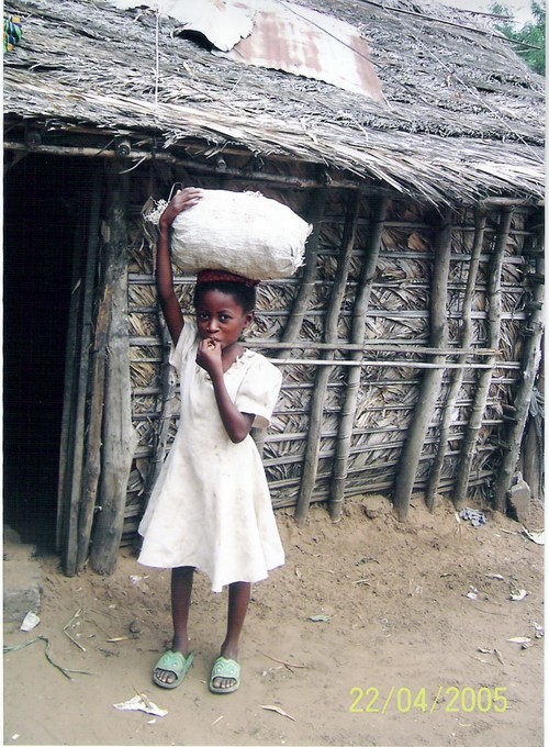 Una bambina di Kenge che porta sulla testa un sacco con i tuberi di manioca.