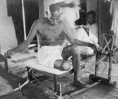 Foto che ritrae Gandhi intento a filare