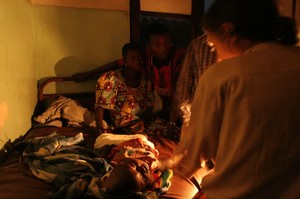 Ospedale di Kimbau: questa bimba non ce l'ha fatta. Arrivata in pediatria in coma epatico, è morta alle 5 del mattino. Sullo sfondo, i genitori.