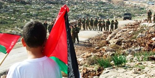 Bambino palestinese di fronte allo schieramento di soldati israeliani.
