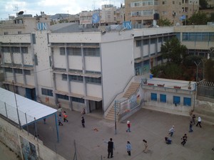 Bethlehem: campo profughi di Aida. La scuola delle Nazioni Unite, crivellata dei colpi degli israeliani. Piu' sotto, i bambini giocano.