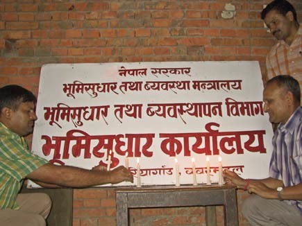 Pittori che cancellano i cartelli che indicano 'governo di sua maestà' e scrivono 'governo del Nepal'. 