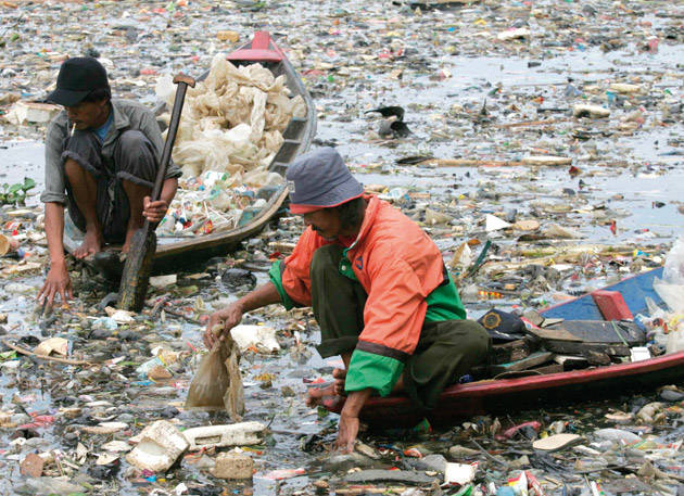 Uomini indonesiani raccolgono rifiuti sul fiume Citarum per il riciclaggio